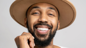 Photo of George Johnson smiling wearing a brown hat.