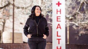 Student Maria Freyta, smiling and walking in front of the Health Center sign