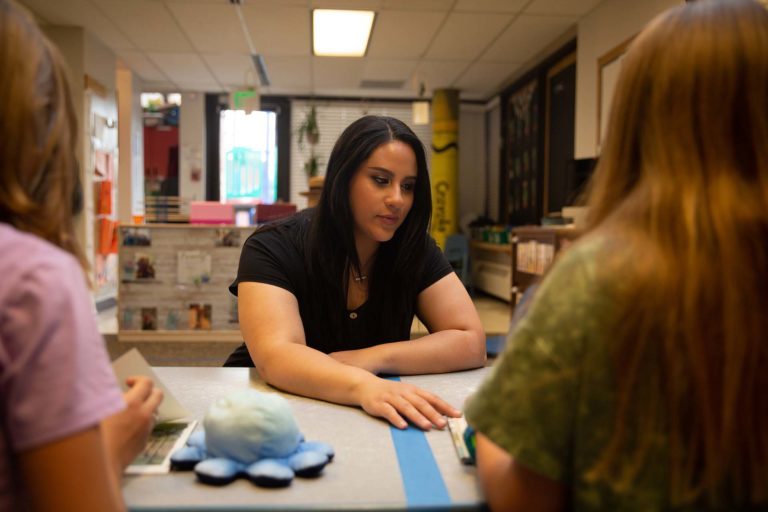 A student having a conversation with two other people at a table