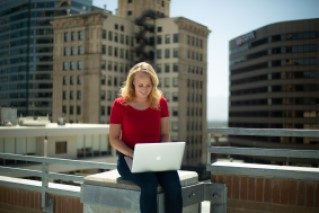 MSU Denver student studying with the Denver skyline behind her