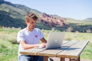 MSU Denver online student studying with a red rock formation in the distance