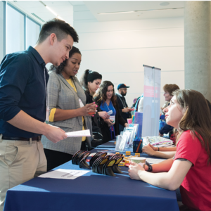 A student taking to a person talking to a recruiter at a table