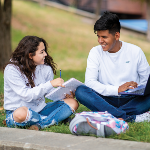 Two students sitting in the grass studying