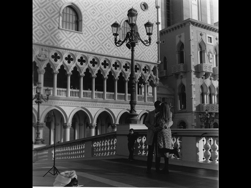 Couple kissing in front of venetian type architecture.