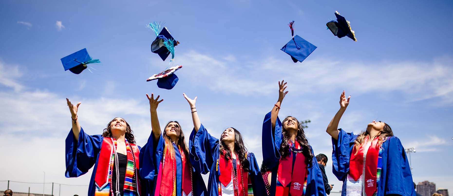 MSU Denver graduates throwing their caps in the air.