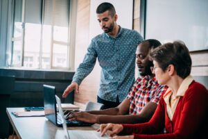 Older adults working on computers with younger adult helping them