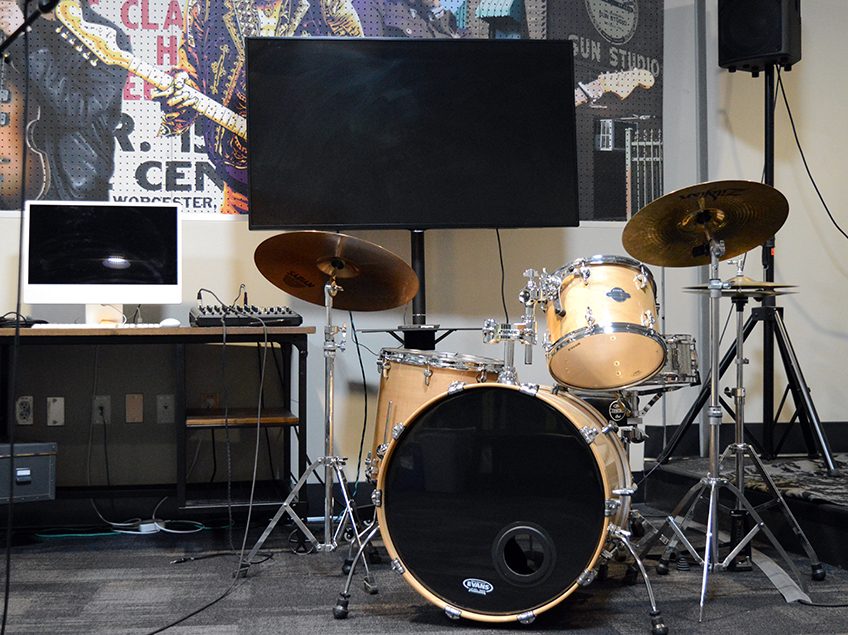 A drumset, monitor and computer in a classroom