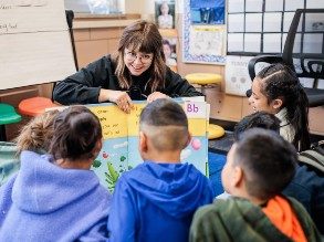 Student-teacher Amber Osborn holds a posterboard with the alphabet in front of a classroom of students