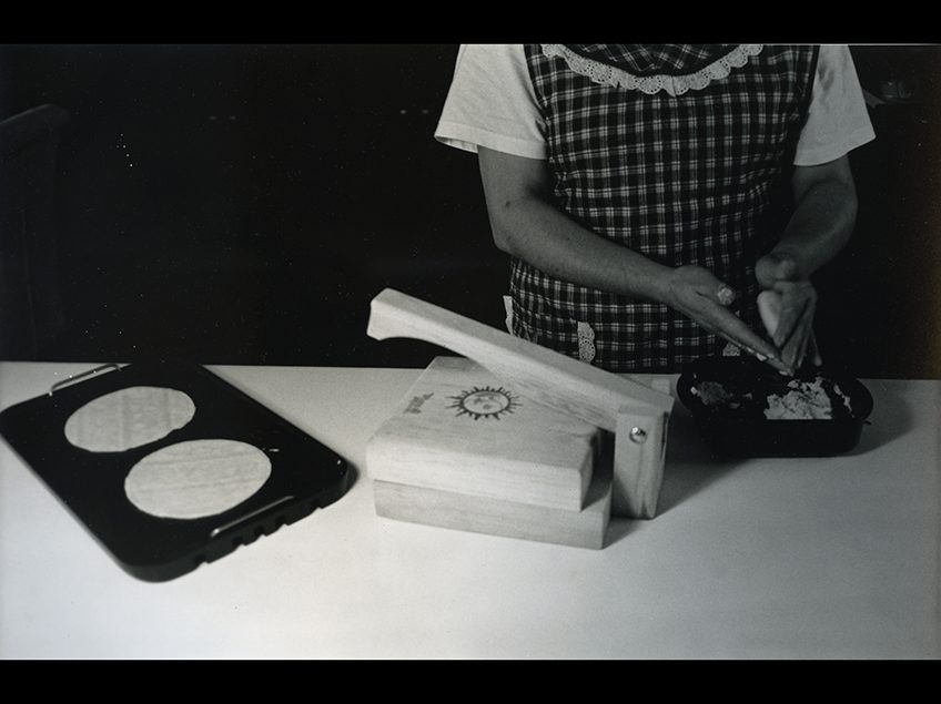 Black and white image of a woman making tortillas.