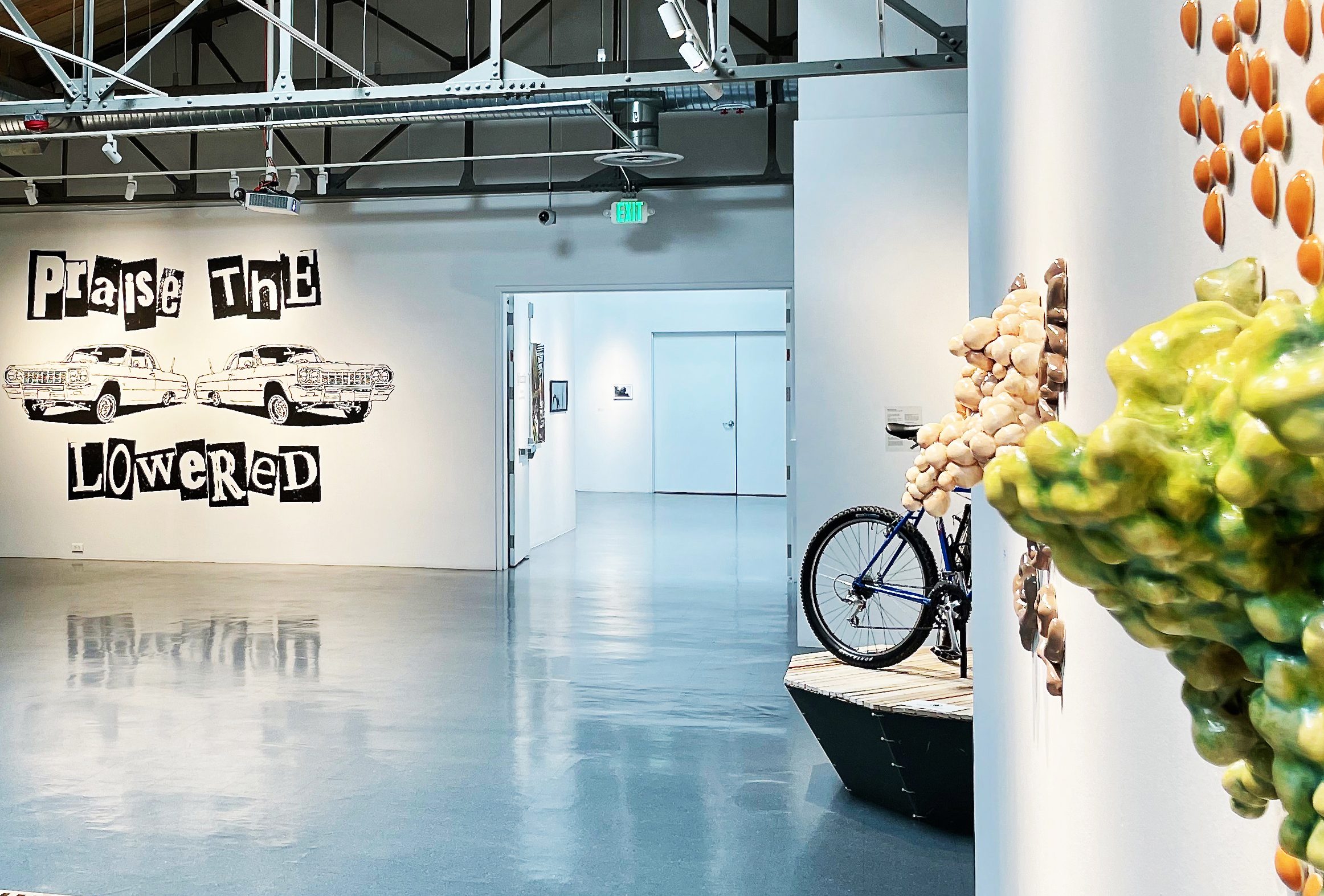 Gallery space with tall ceilings, large wall mural and ceramic sculpture in foreground.