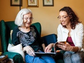 MSU Denver student Jackie Schwartz, right, reads about Egyptology with resident Jeanne Dietrich in her room at Clermont Park Senior Living Community