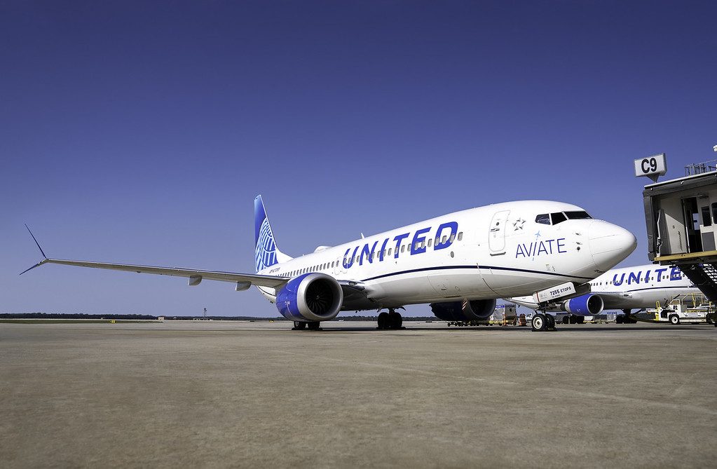 A United B-737 aircraft parked by a jet bridge.
