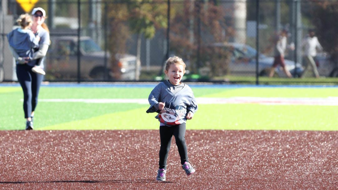 Young girl running on the softball field at the 2023 Roadrunners 5k