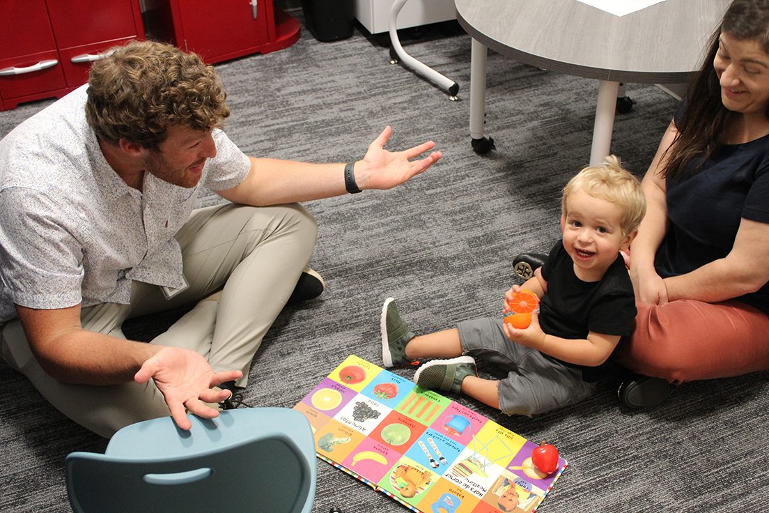 MS SLP graduate student (left) working with toddler and parent (right)