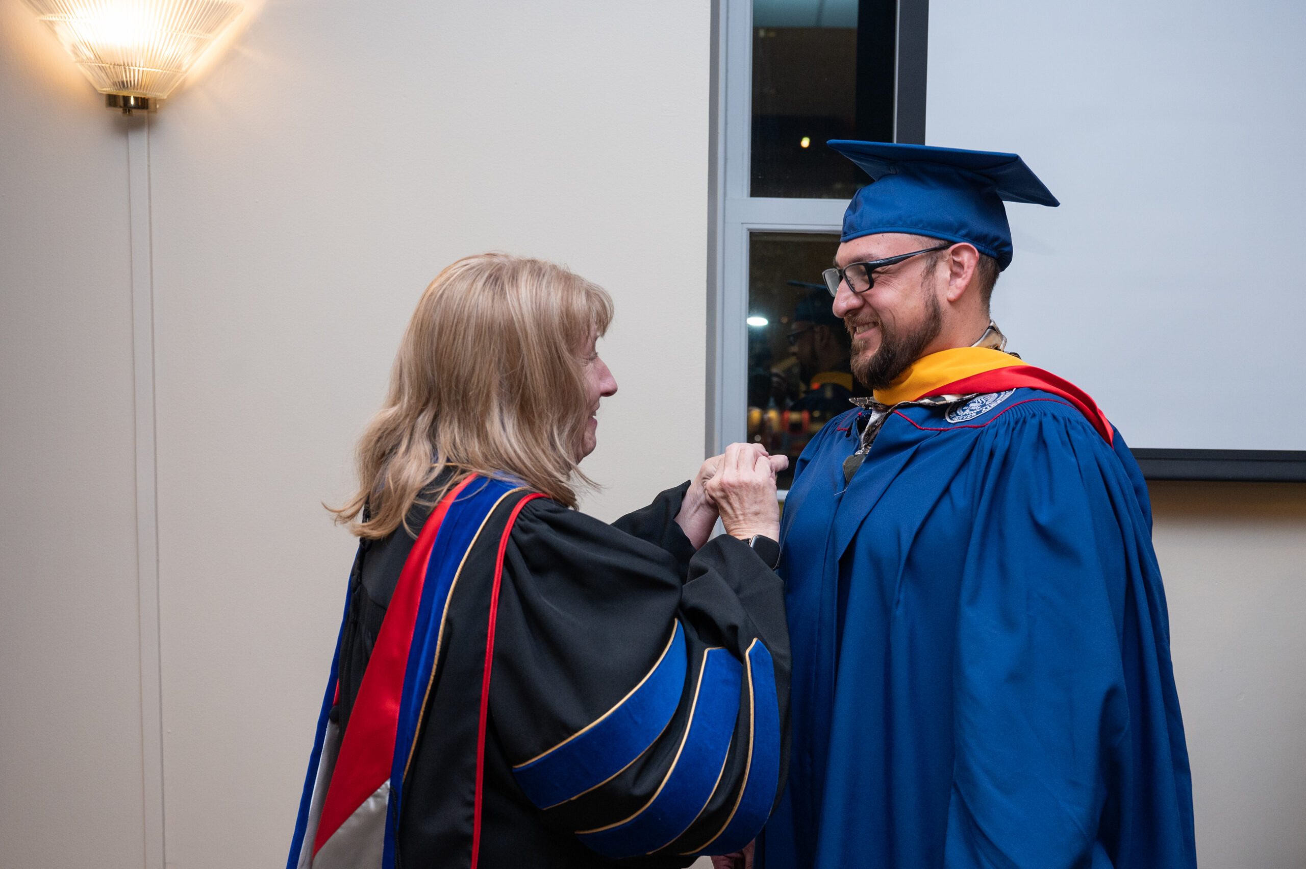 Dr. Denise Mowder, J.D. pinning the Cybersecurity pin on an MSU Denver graduate of the Master of Science in Cybersecurity program.