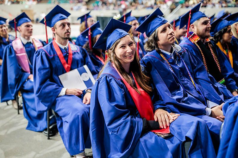 Happy graduates sit in the audience prepared to receive their diplomas at MSU Denver Spring 2023 commencement ceremony.