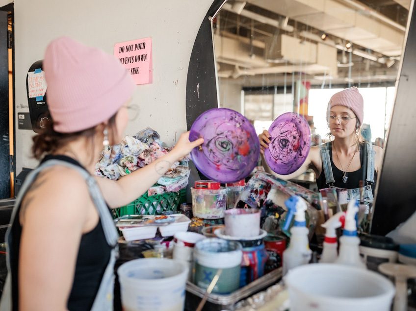 MSU Denver student, Katelin Knudsen, reaches for a paint palette in Painting and New Contexts class on May 3, 2023. Photo by Alyson McClaran