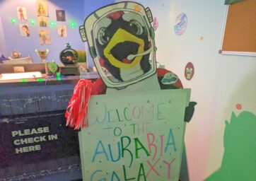 Photo from the 2022 office decorating party of a cutout of Rowdy with a space helmet on, holding a sign that says, 