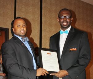 Photo of Rashad Anderson standing next to his mentor receiving a plaque.