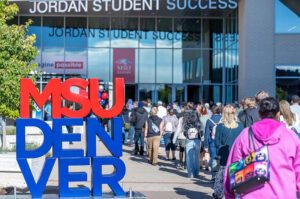 students walking outside JSSB with MSU Denver sign in foreground.
