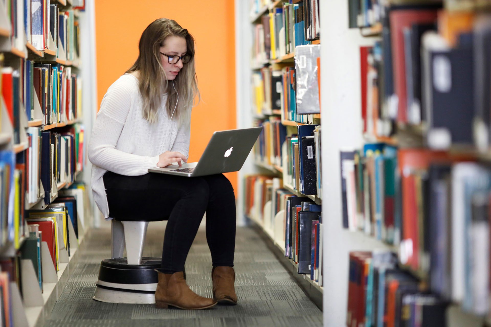 Student sitting in the library working on a laptop computer.