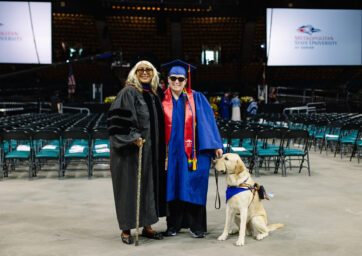 Dawn Bookhardt standing with a visually-impaired student and his dog at commencement in May 2023