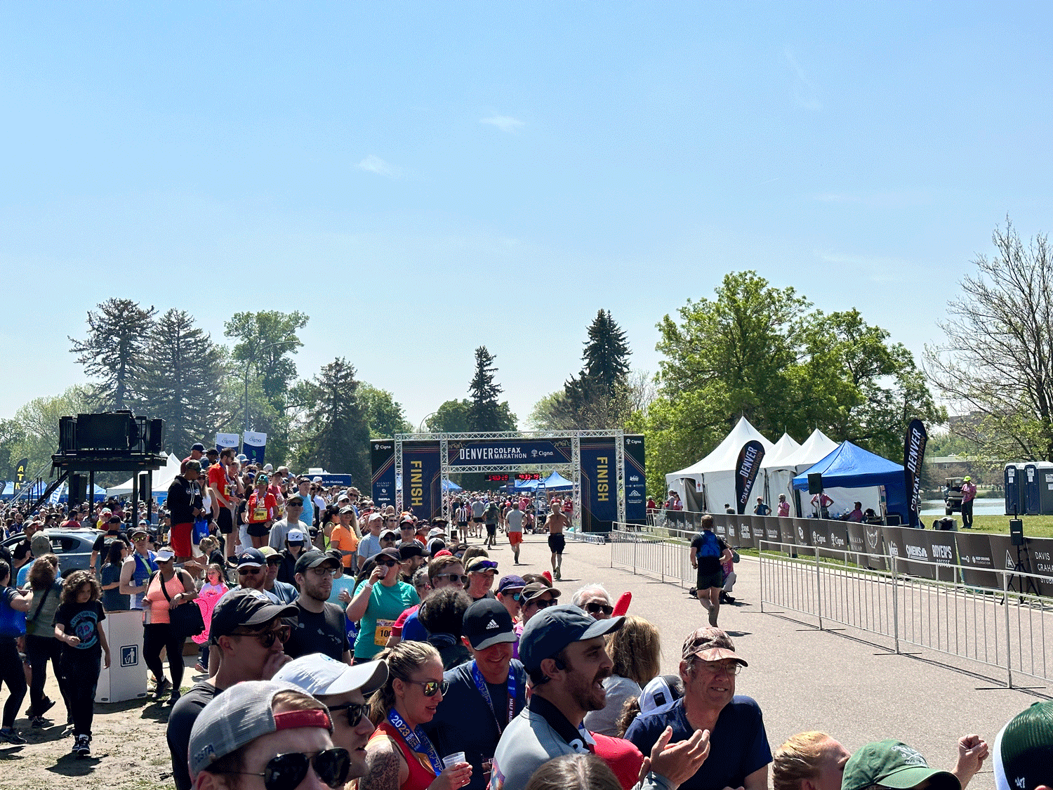 Runners crossing the finish line in front of a large crowd at the 2023 Denver Colfax Marathon