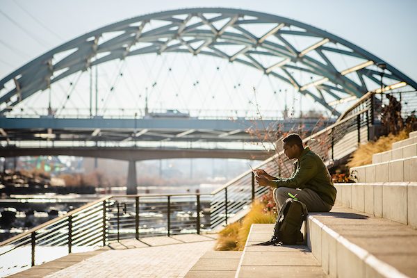 Student with laptop outside at Confluence Park in Denver