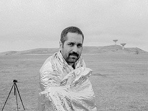 Professor Nima Bahrehmand outside in a desert setting wrapped in a reflective blanket next to a tripod.