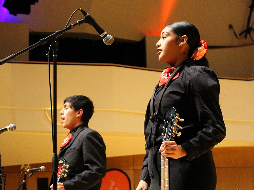 two mariachi singers performing onstage