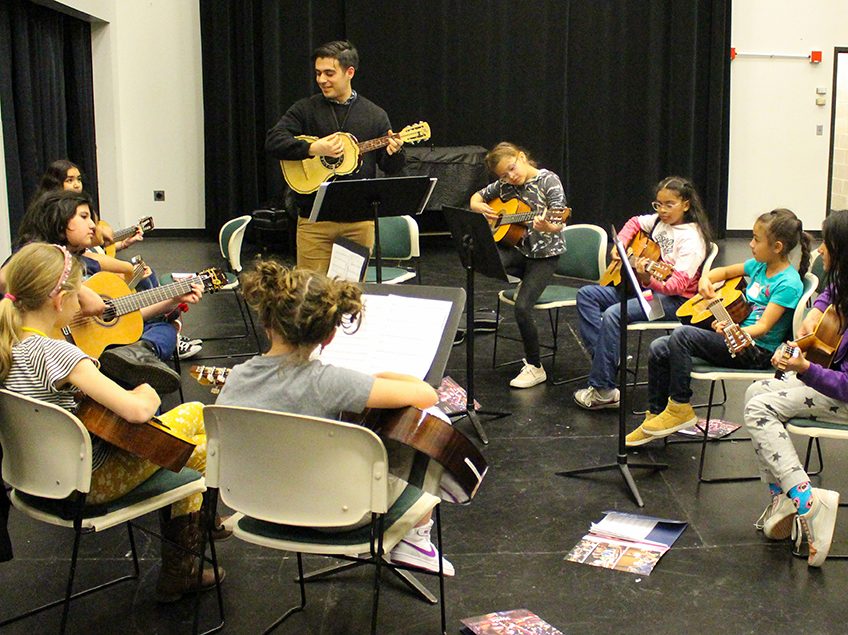 group of children learning guitar