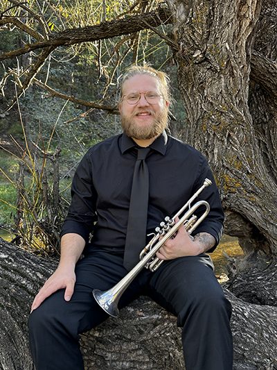 Braden Collison in forest holding trumpet