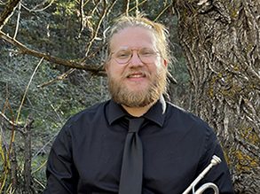 Braden Collison in forest holding trumpet