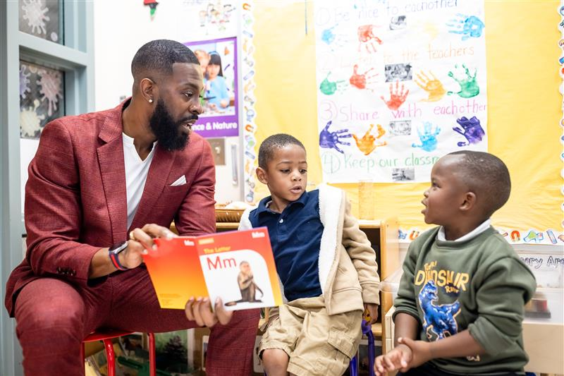 Decorative: Dr. Rashad Anderson reads two elementary aged boys a book.