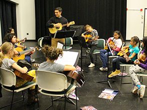 Group of kids learning guitar