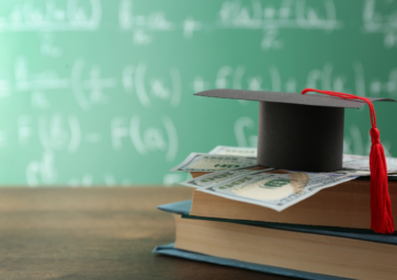 College cap sitting on $100 bill and text books