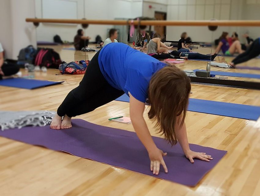 Decorative: Image of Inclusive Higher Education student performing downward dog in a yoga class.