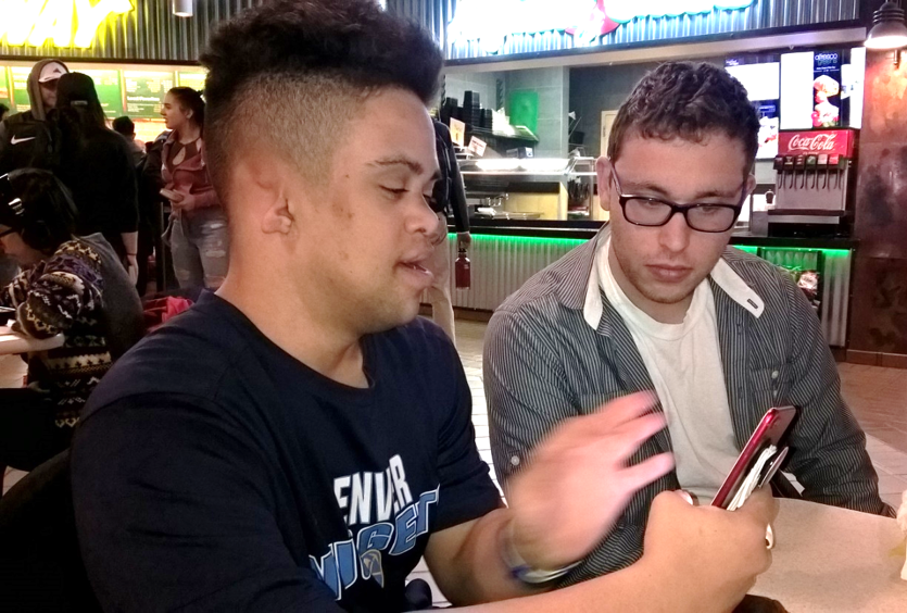 Decorative: One Inclusive higher education student shows another student something on his phone
