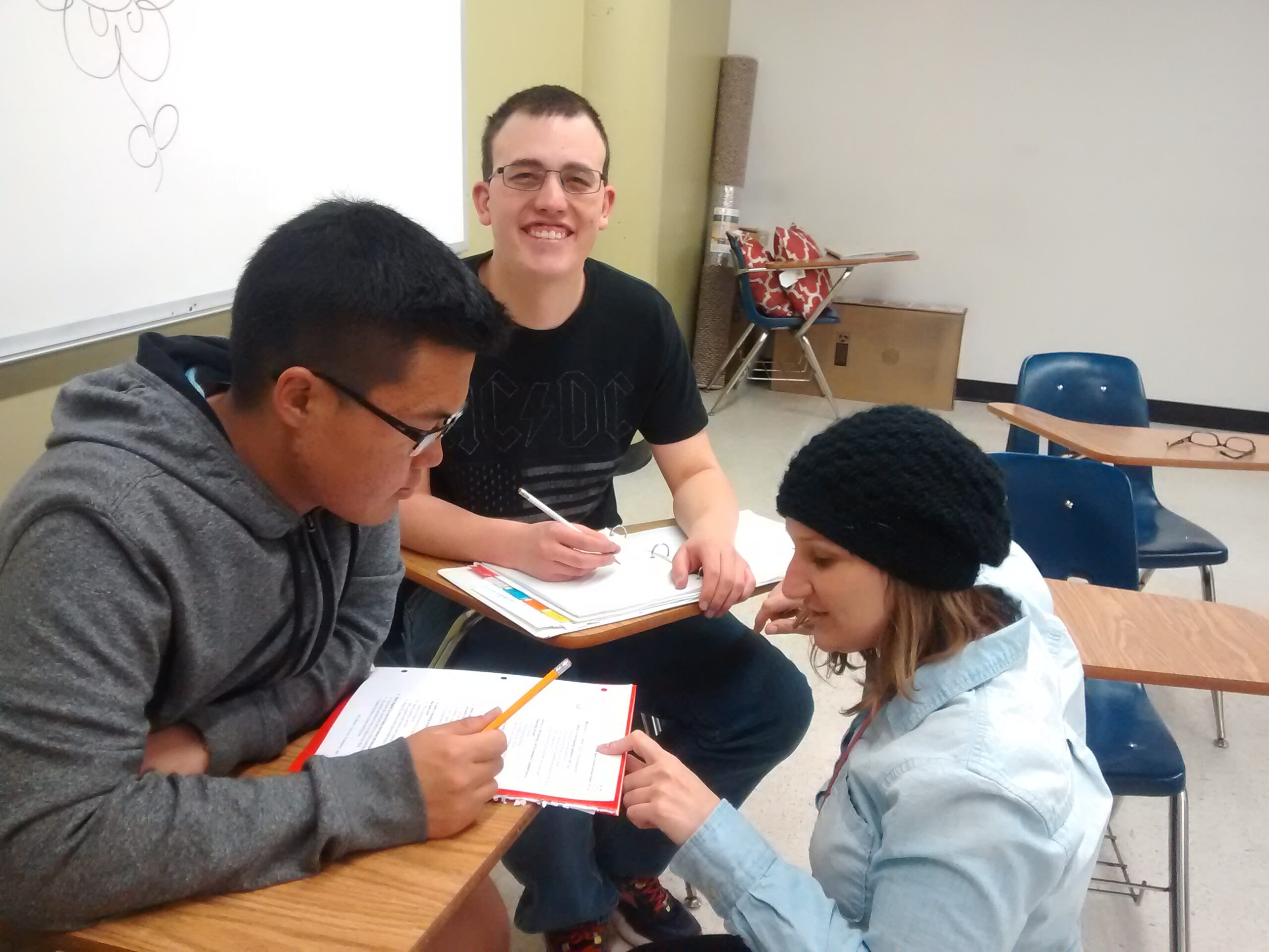 Decorative: three Inclusive Higher Education students work on group work in a classroom.