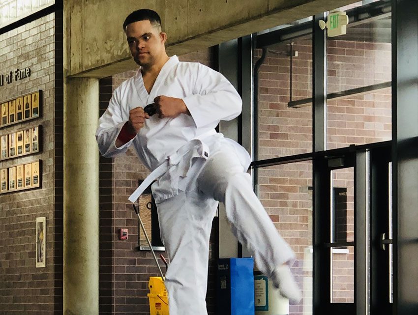 Decorative: Inclusive Higher Education student wearing a gi does a jumping kick.