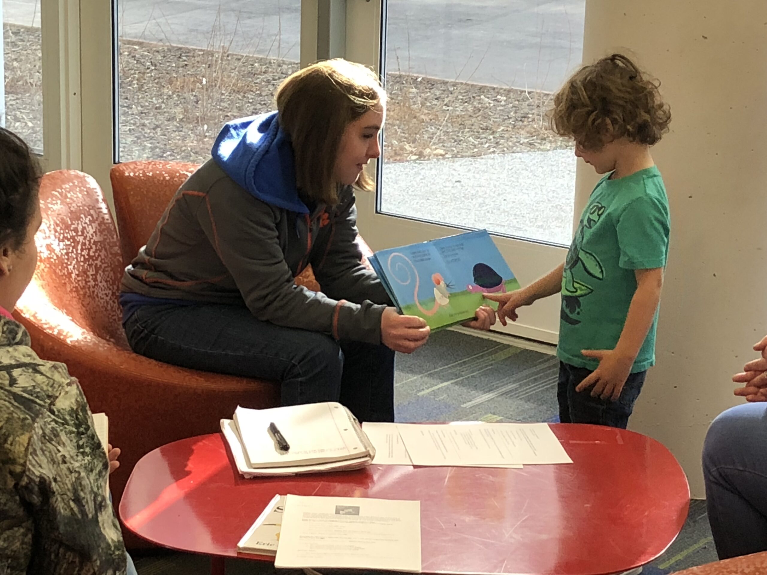 Decorative: An Inclusive Higher Education Student reads picture book to a young child