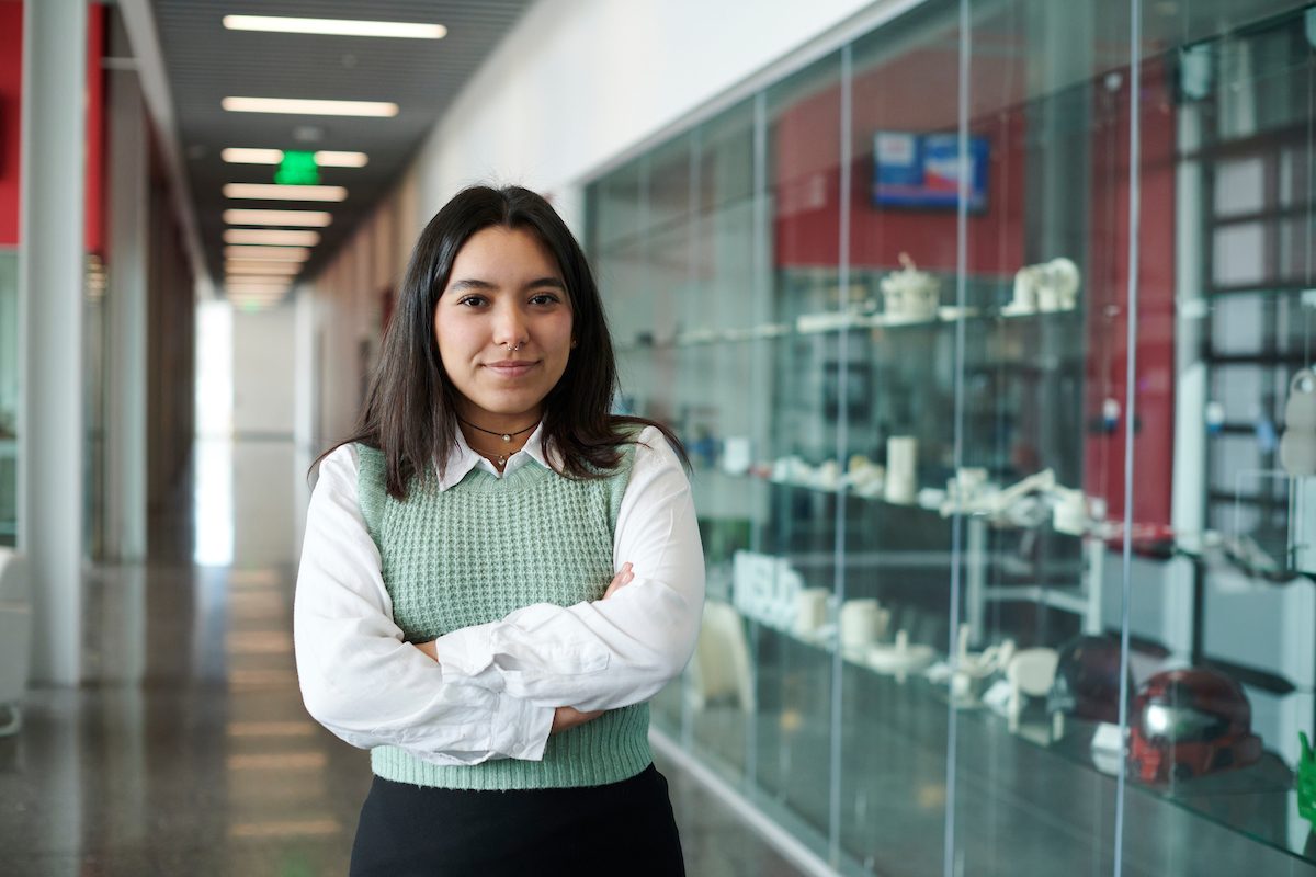 Student standing in a hallway with arms crossed.