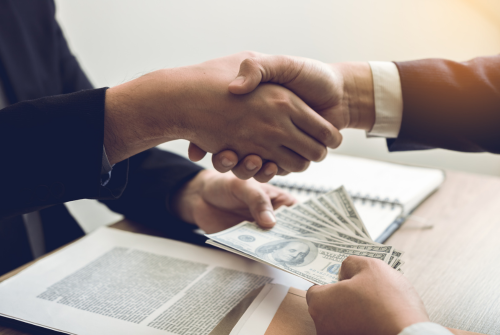 Shaking hands and exchanging cash to demonstrate a business deal