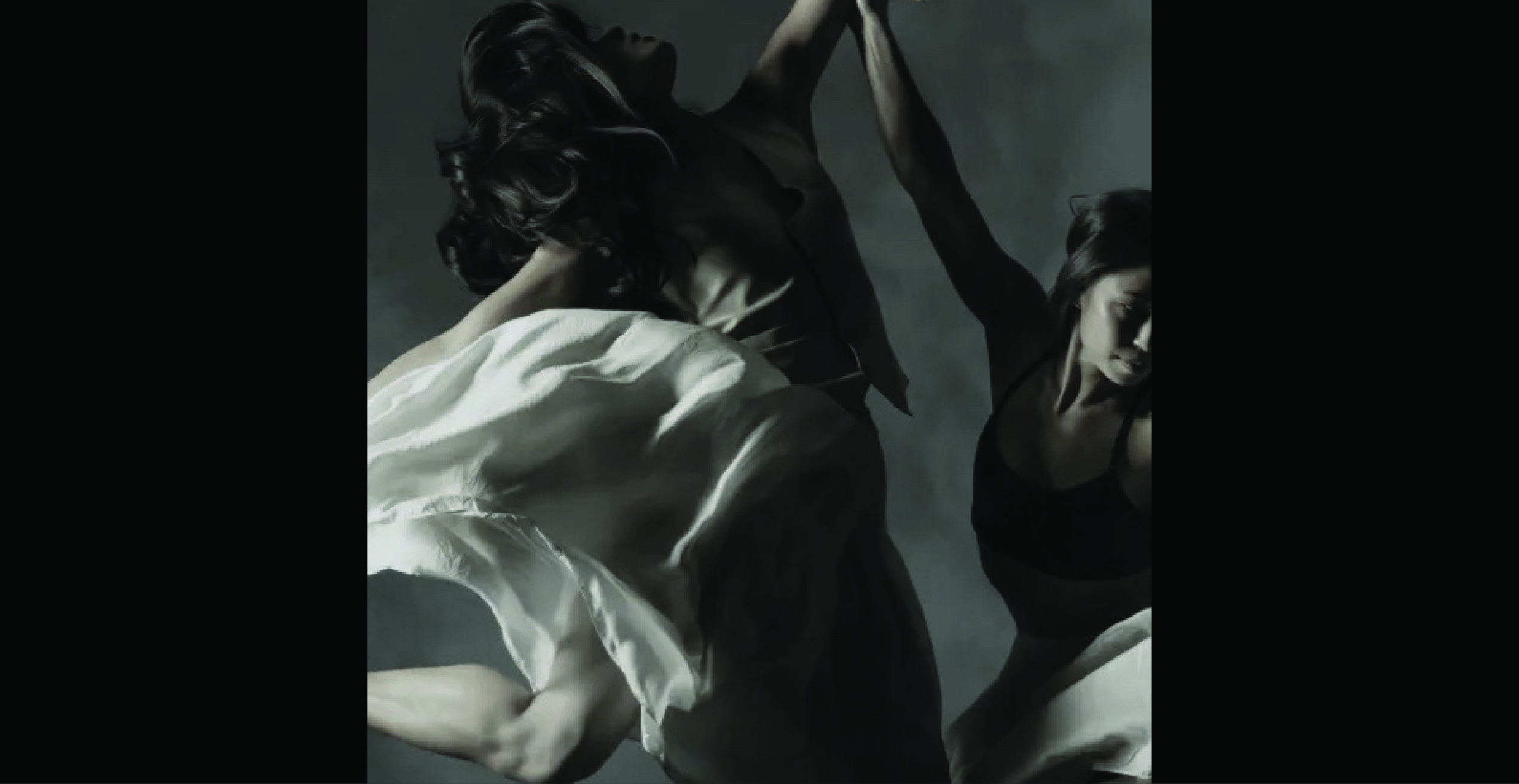 Two women jumping in the air with their white dresses floating around them. They are in a white and black and one has hair covering her face.