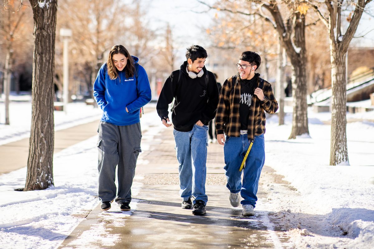Three students walking on campus in the snow