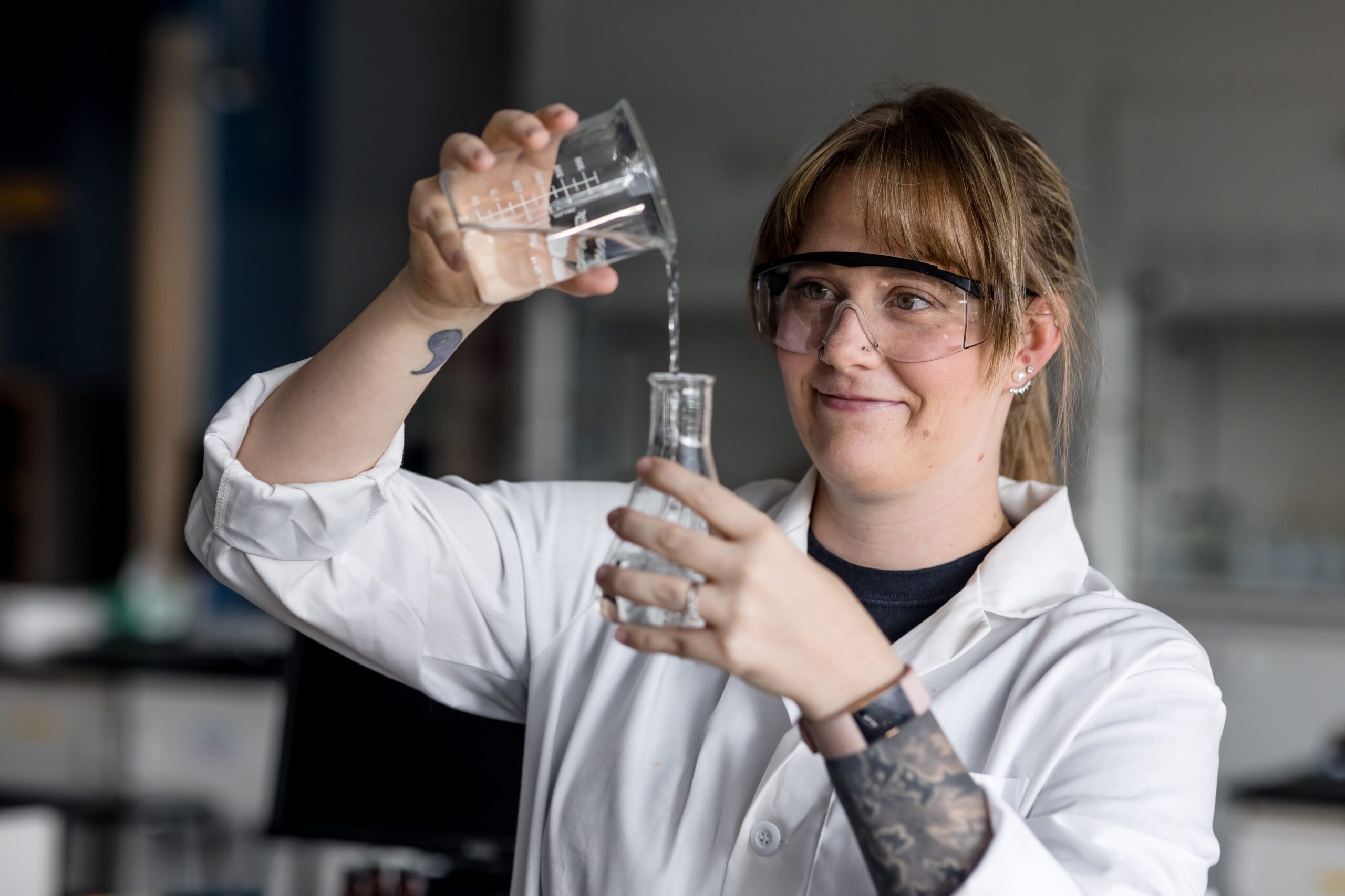 Autumn Gilmore, a chemistry and biochemistry junior at Metropolitan State University, pouring liquid from one beaker into another.