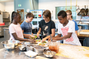 Kids making a pizza in the School of Hospitality