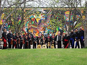 Group photo of Mariachi los Correcaminos de MSU Denver in front of colorful mural