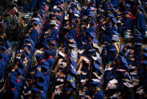 students sit at commencement.