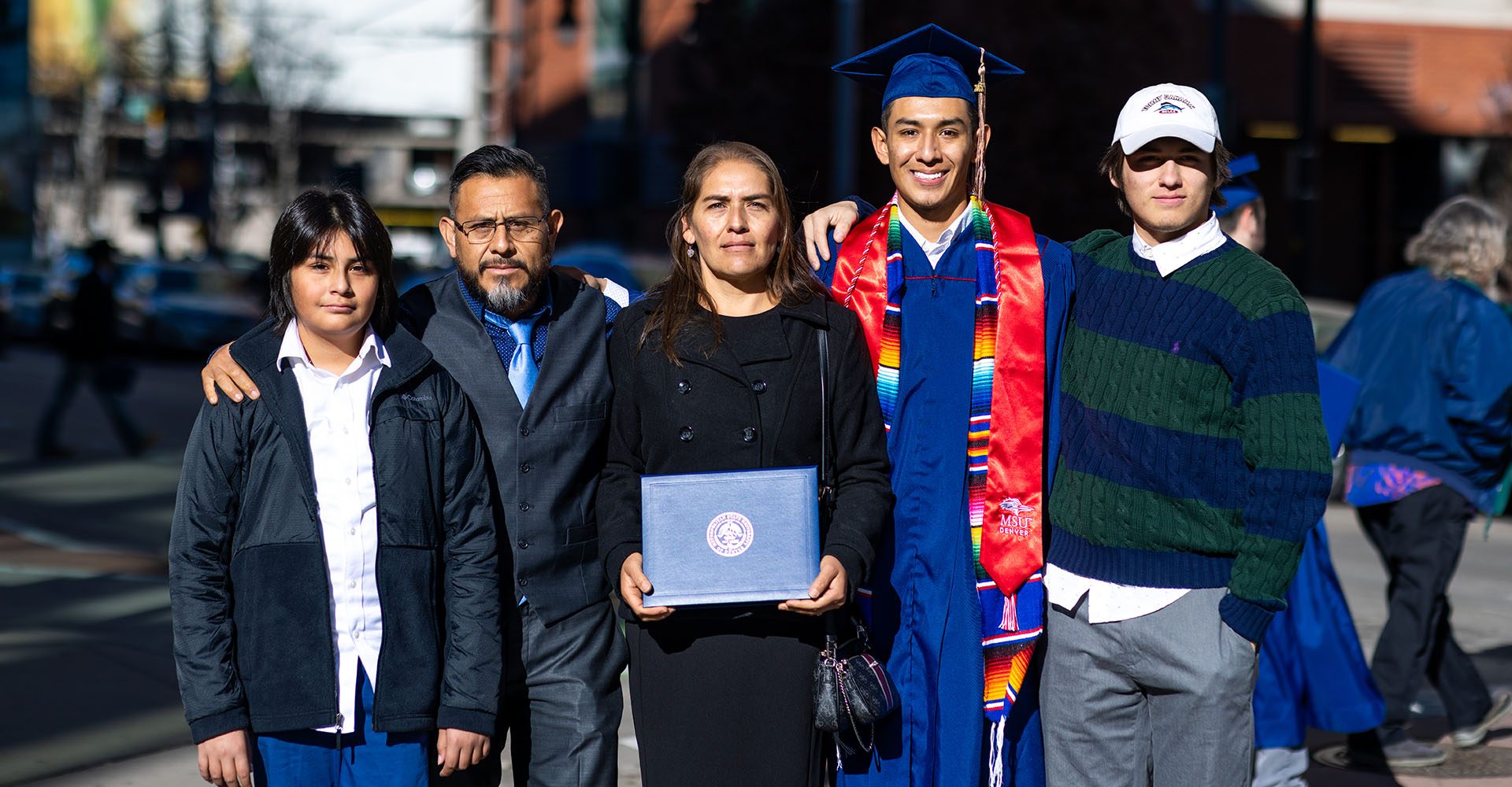 MSU Denver graduate poses with his family in Downtown Denver.
